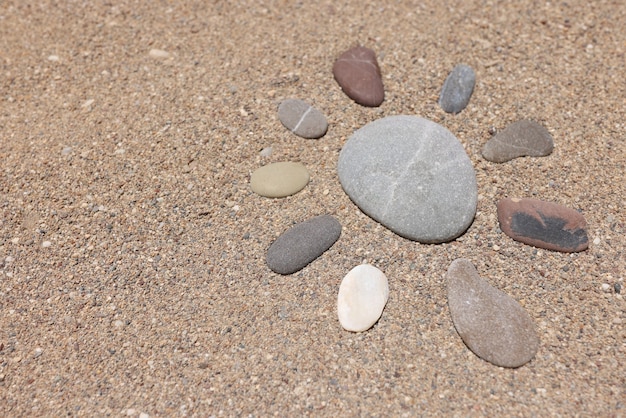Sonnenfigur ist aus Steinen auf Strandsand