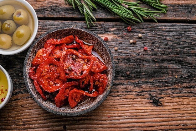 Sonnengetrocknete Tomaten in Holzhintergrund Getrocknete Tomaten mit Olivenöl Rosmarin KräuterKnoblauch