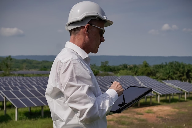 Sonnenkollektoren des Solarparks mit Ingenieuren, die ein Tablet verwenden, um den Betrieb des Systems zu überprüfen Alternative Energie für die weltweite Energieeinsparung Photovoltaikmodulkonzept für saubere Energieerzeugung