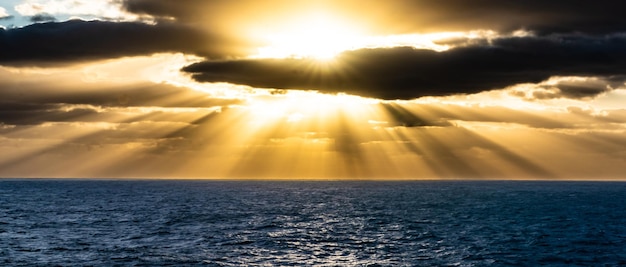 Foto sonnenlicht, das während des sonnenuntergangs durch wolken über dem meer strömt