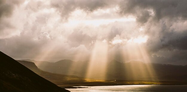 Foto sonnenlicht strömt durch wolken über die landschaft