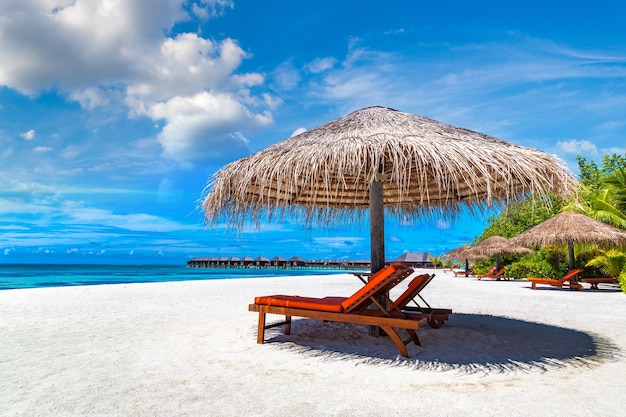 Sonnenliege und Sonnenschirm am tropischen Strand auf den Malediven