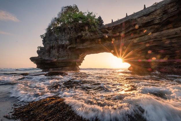 Sonnenschein durch felsige Klippe auf Küste bei Sonnenuntergang