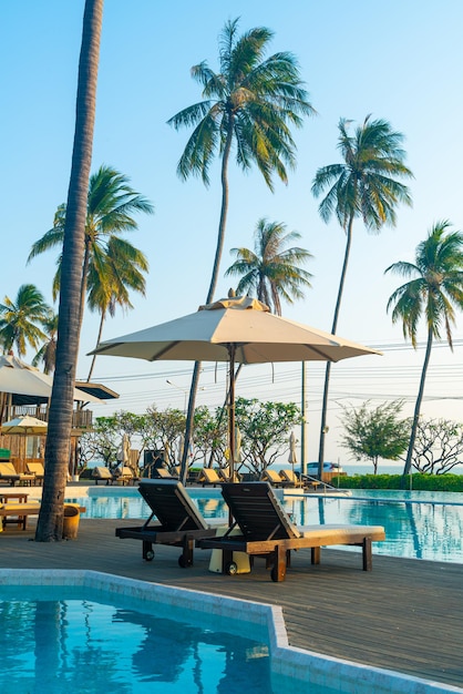 Sonnenschirm mit Bettpool rund um den Pool mit Ozean-Meer-Hintergrund - Urlaubs- und Urlaubskonzept