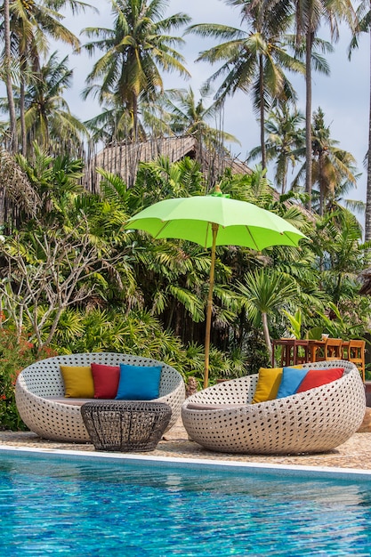 Sonnenschirm und Liegestühle neben dem Pool an der tropischen Küste für Urlaub und Entspannung für Touristen, Thailand. Reise- und Naturkonzept