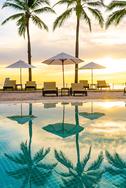 Sonnenschirm und Stuhl um den Pool im Hotelresort mit Sonnenaufgang am Morgen