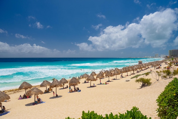 Sonnenschirme an einem Sandstrand mit azurblauem Wasser an einem sonnigen Tag in der Nähe von Cancun Mexiko