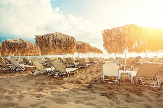 Sonnenschirme und Sonnenliegen am Meeresstrand vor Himmelswolken Hintergrund Sommerurlaubskonzept