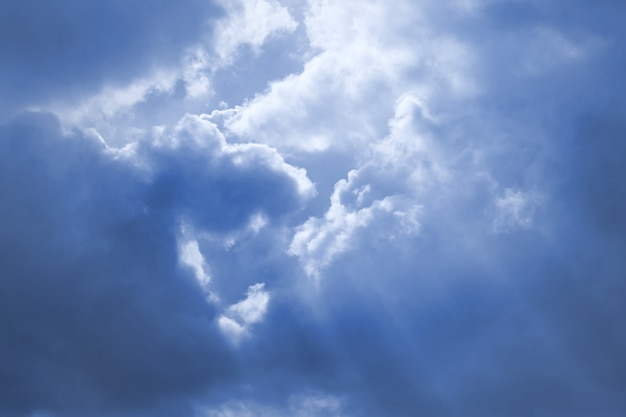 Sonnenstrahlen brechen durch die dunkelblauen Wolken