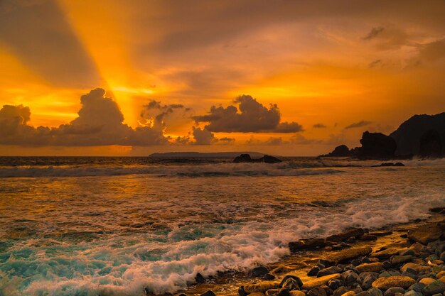 Foto sonnenuntergang am felsigen strand in papuma jember ost-java indonesien