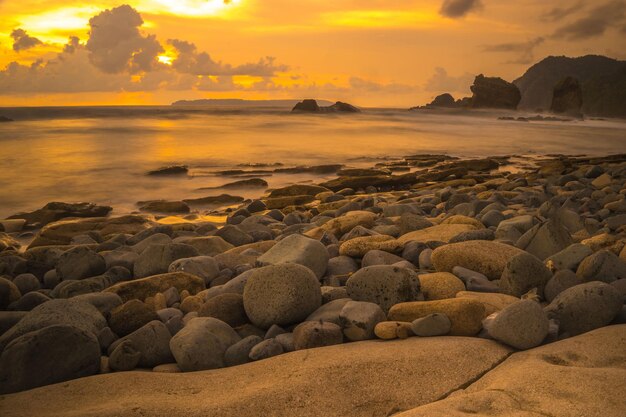 Foto sonnenuntergang am felsigen strand in papuma jember ost-java indonesien