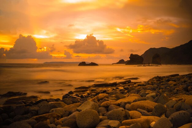 Foto sonnenuntergang am felsigen strand in papuma jember ost-java indonesien