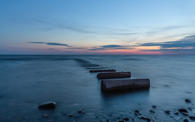 Sonnenuntergang am Meer mit Betonblöcken im Wasser