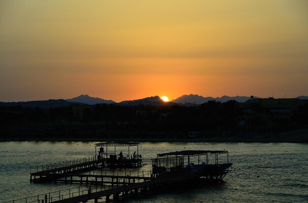 Sonnenuntergang am Meer mit Pier und Bergen