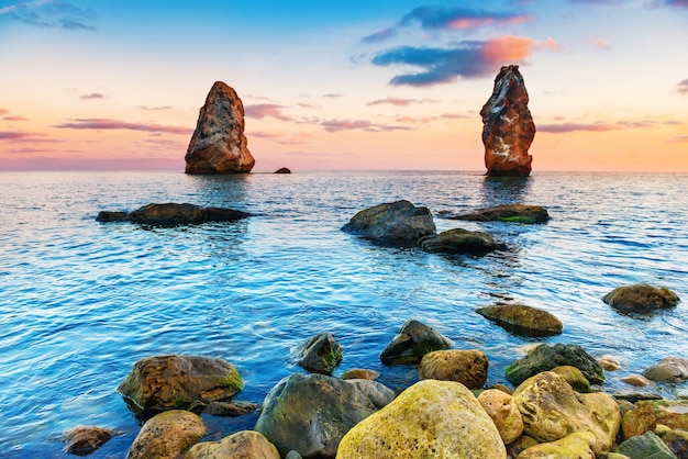 Sonnenuntergang am Meer über großen Felsen. Landschaft mit Küste und dramatischem Himmel