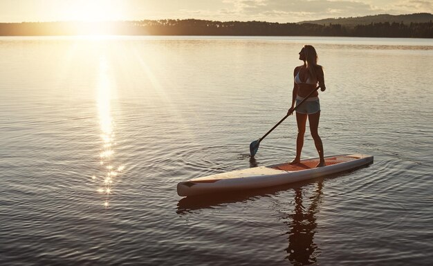Sonnenuntergang am See und Frau auf dem Paddleboard für Entspannung Wassersport und Urlaub am Fluss für den Tourismus Sonnenlicht Sommer und Urlaub in Deutschland für weibliche Person Aussicht und Reise Fitness für Abenteuer
