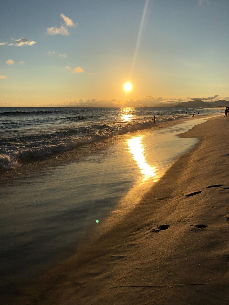 Foto sonnenuntergang am strand barra da tijuca in rio de janeiro, brasilien. meer mit ruhigen wellen.
