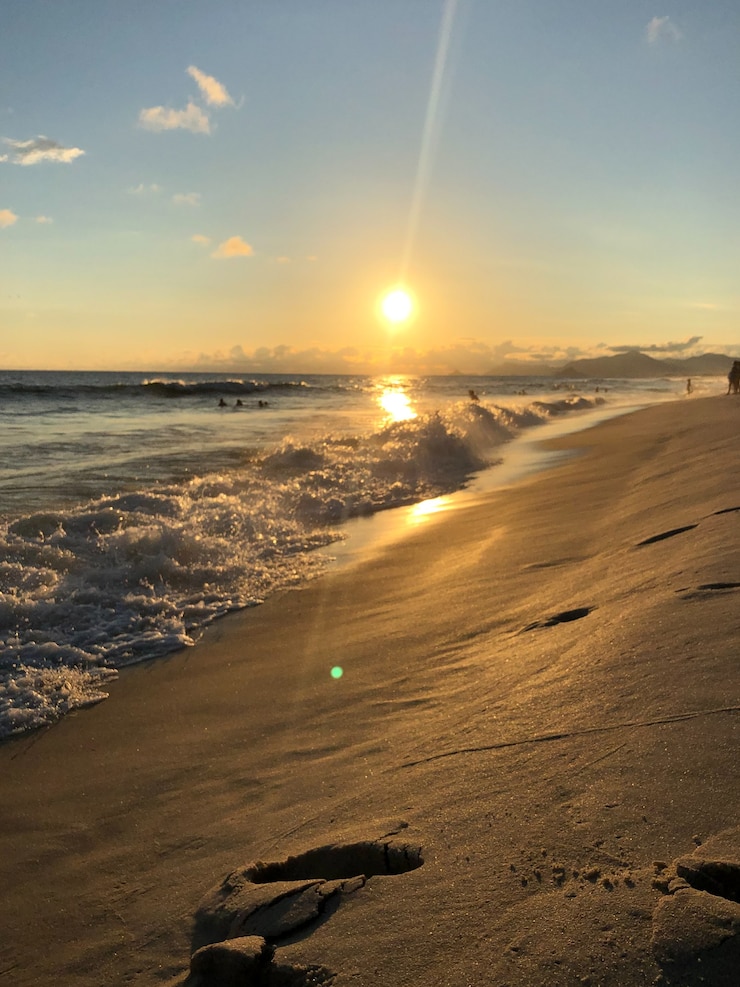 Foto sonnenuntergang am strand barra da tijuca in rio de janeiro, brasilien. meer mit ruhigen wellen.