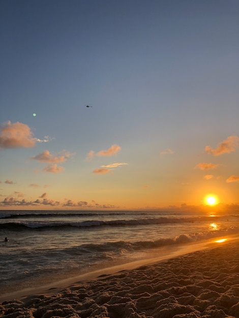 Sonnenuntergang am Strand Barra da Tijuca in Rio de Janeiro, Brasilien. Meer mit ruhigen Wellen.