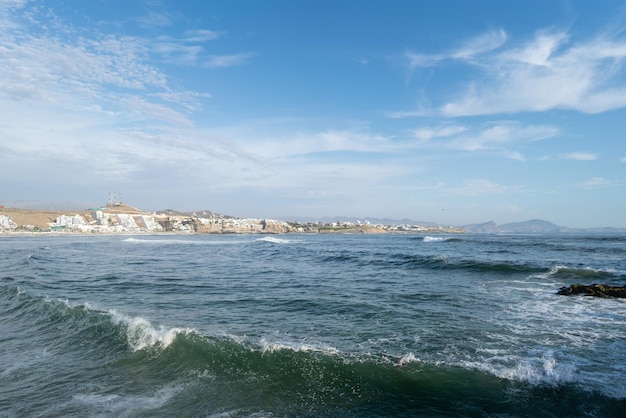 Sonnenuntergang am Strand mit blauem Himmel und Meer und weißen Wolken. Felsensteg. Punta Hermosa, Lima.