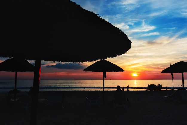 Sonnenuntergang am Strand mit Sonnenschirmen