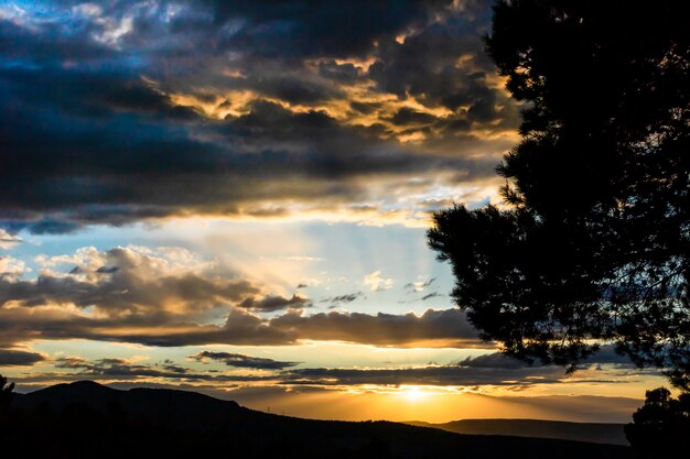 Sonnenuntergang an einem Tag mit Wolken und Sonnenstrahlen im Berg.