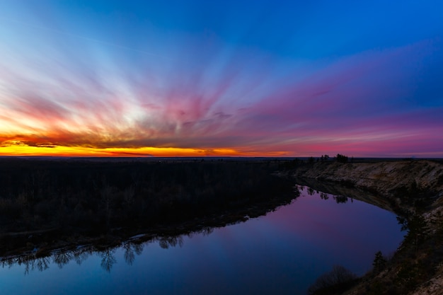 Sonnenuntergang auf dem Hintergrund der glatten Oberfläche des Flusses.