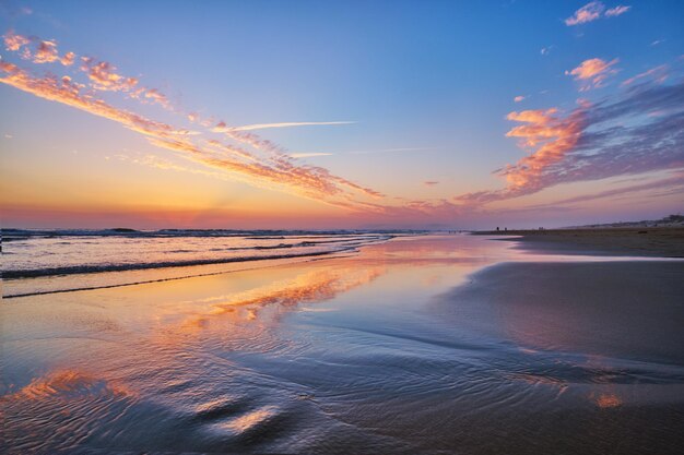 Sonnenuntergang im Atlantischen Ozean mit schwimmenden Wellen am Strand von Font da Telha, Portugal