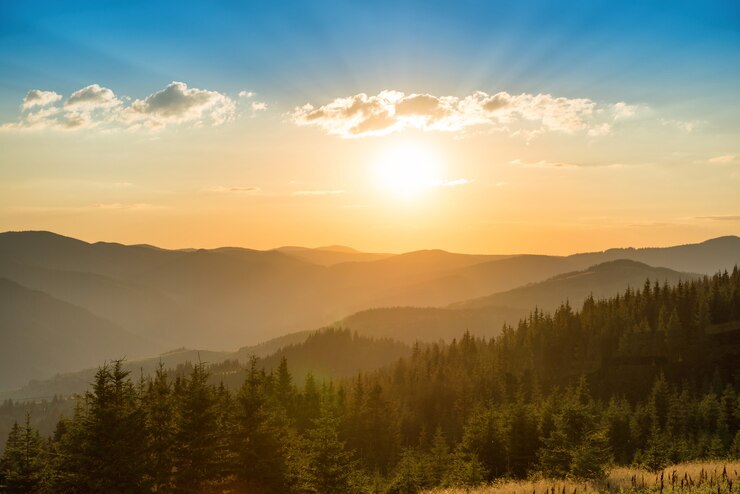 Sonnenuntergang in den Bergen mit Wald und großer strahlender Sonne am dramatischen Himmel