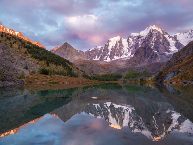 Sonnenuntergang in Magenta-Tönen. Gletschersee hoch in den Bergen. Stimmungsvolle lila Landschaft mit einem See in einem verschneiten Hochtal. Altai-Gebirge.