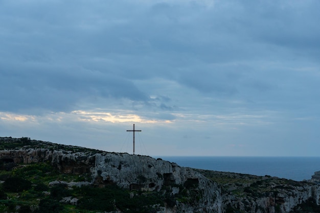 Sonnenuntergang in Mellieha mit dem Meeresboden und einem Kreuz in der Ferne