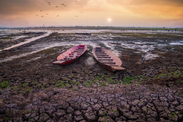 Sonnenuntergang oder Sonnenaufgang mit trockenem Land und Fischerboot