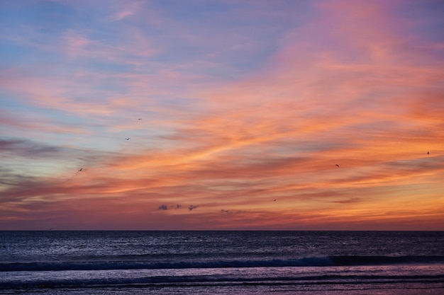 Sonnenuntergang Ozeanstrand von Spanien Andalusien. Atlantik wellt Hintergrund heller magischer Sommersonnenunterganghimmel