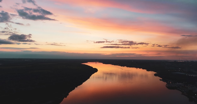 Sonnenuntergang über dem Fluss. Flusslandschaft. Sonnenuntergang mit Reflexion über das Wasser. Panorama