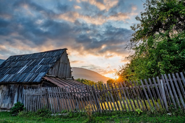 Sonnenuntergang über dem Haus und grünen Bäumen auf dem Land