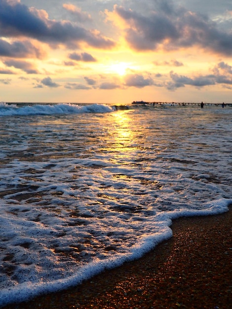 Sonnenuntergang über dem Meer Schöner Sonnenuntergang Schäumende Wellen rollen über das sandige Ufer Vityazevo Anapa Schwarzes Meer Touristenmekka Kurort Bunte Wolken am Abendhimmel Die Strahlen spiegeln sich im Wasser