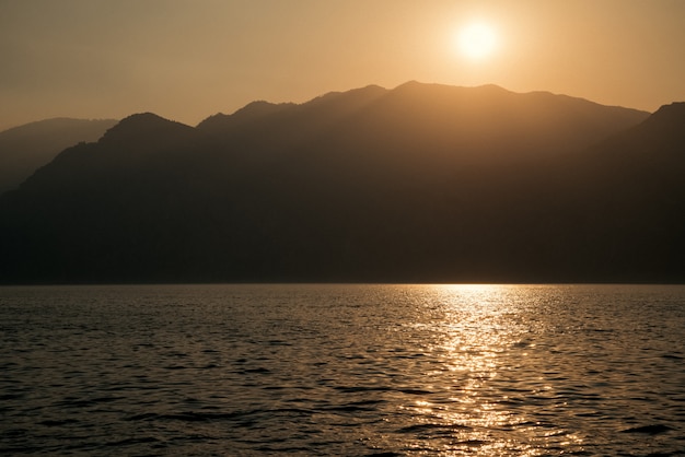 Sonnenuntergang über dem See auf dem Hintergrund der Bergkette