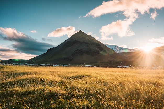 Sonnenuntergang über dem Stapafell-Berg und leuchtende Wiese im Dorf Arnarstapi im Sommer in Island