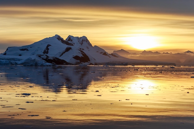 Sonnenuntergang über den Bergen und treibenden Eisbergen in der Lemaire Strait Antarktis