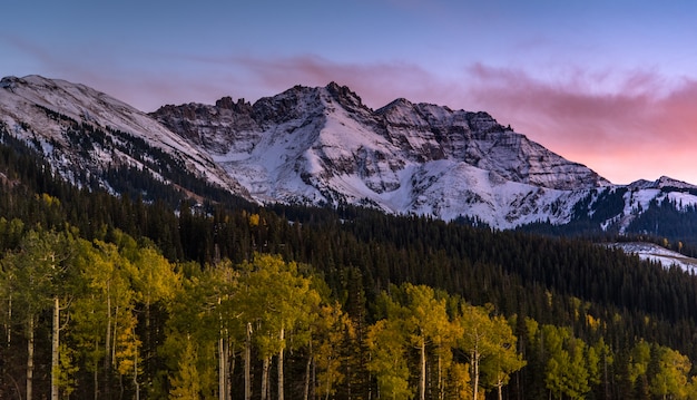 Sonnenuntergang über Herbstwald mit Gebirgshintergrund im Telluride