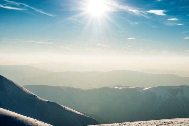 Sonnenuntergang über Hügeln und Bergen mit Schnee