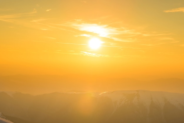 Sonnenuntergang über Hügeln und Bergen mit Schnee