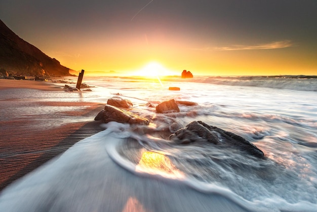 Sonnenuntergang, während Meereswellen die Felsen am Strand von Ilbarritz im Baskenland von Biarritz treffen