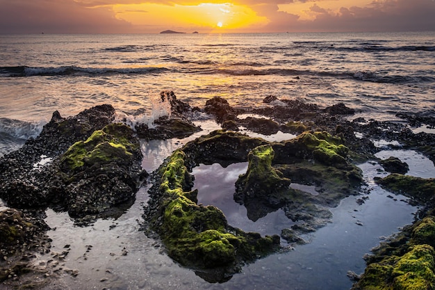 Sonnenunterganglandschaft auf den Strandfelsen im Vordergrund