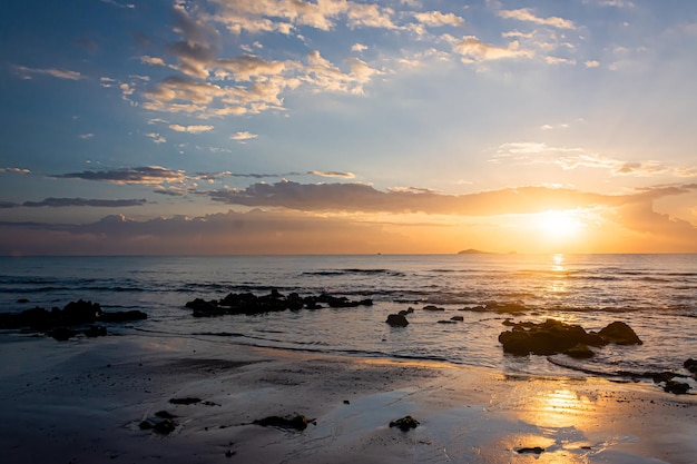 Sonnenunterganglandschaft auf den Strandfelsen im Vordergrund