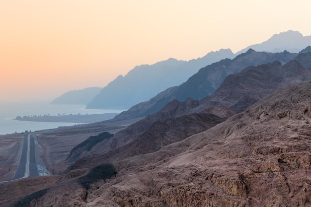 Sonnenunterganglandschaft mit Bergen entlang der Küste des Roten Meeres, die im Abenddunst verschwinden Dahab Ägypten