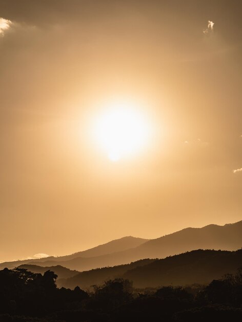 Sonnenuntergangslandschaft mit Berg- und Sonnengoldbeleuchtung unter lebendigem, farbenfrohem Abendhimmel in den Bergen Naturgebirgshimmel und Wolken Sonnenuntergang Konzept