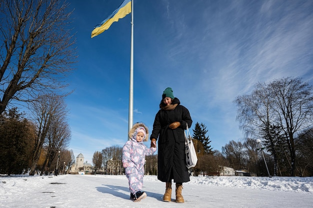 Sonniger, frostiger Wintertag im Park vor dem Hintergrund eines Fahnenmastes mit der ukrainischen Flagge