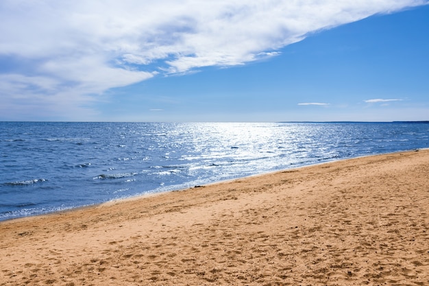 Sonniger Strand, blaues Meer unter blauem Himmel mit weißen Wolken, Sommermeerblick.