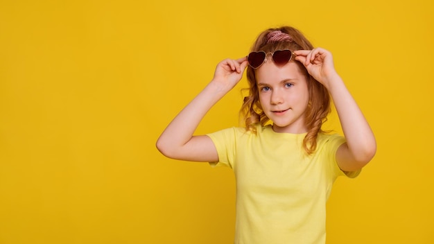 Sonniges Mädchen in gelbem T-Shirt-Mockup auf gelbem Hintergrund Mädchen trägt oder zieht eine Sonnenbrille an